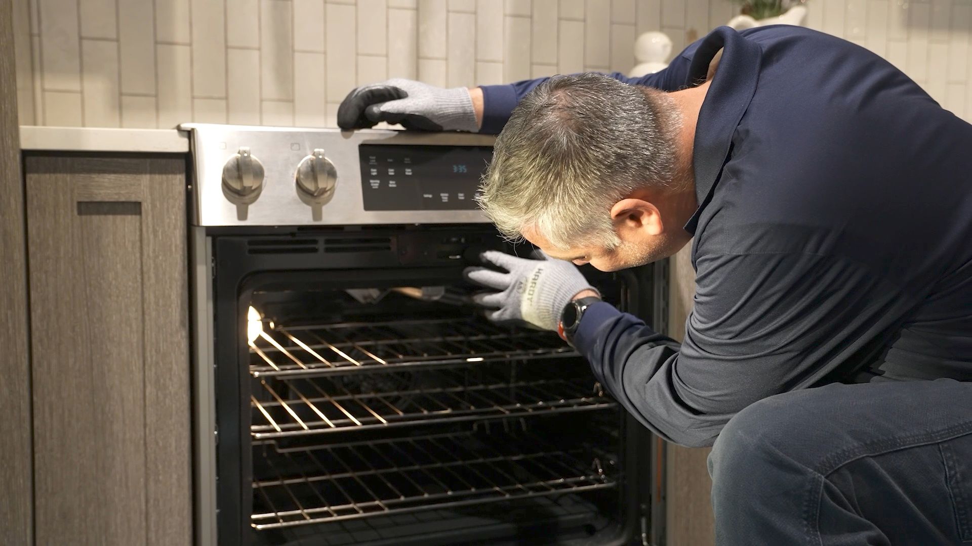 A Yale Appliance technician leaning into an open oven cavity to diagnose a problem