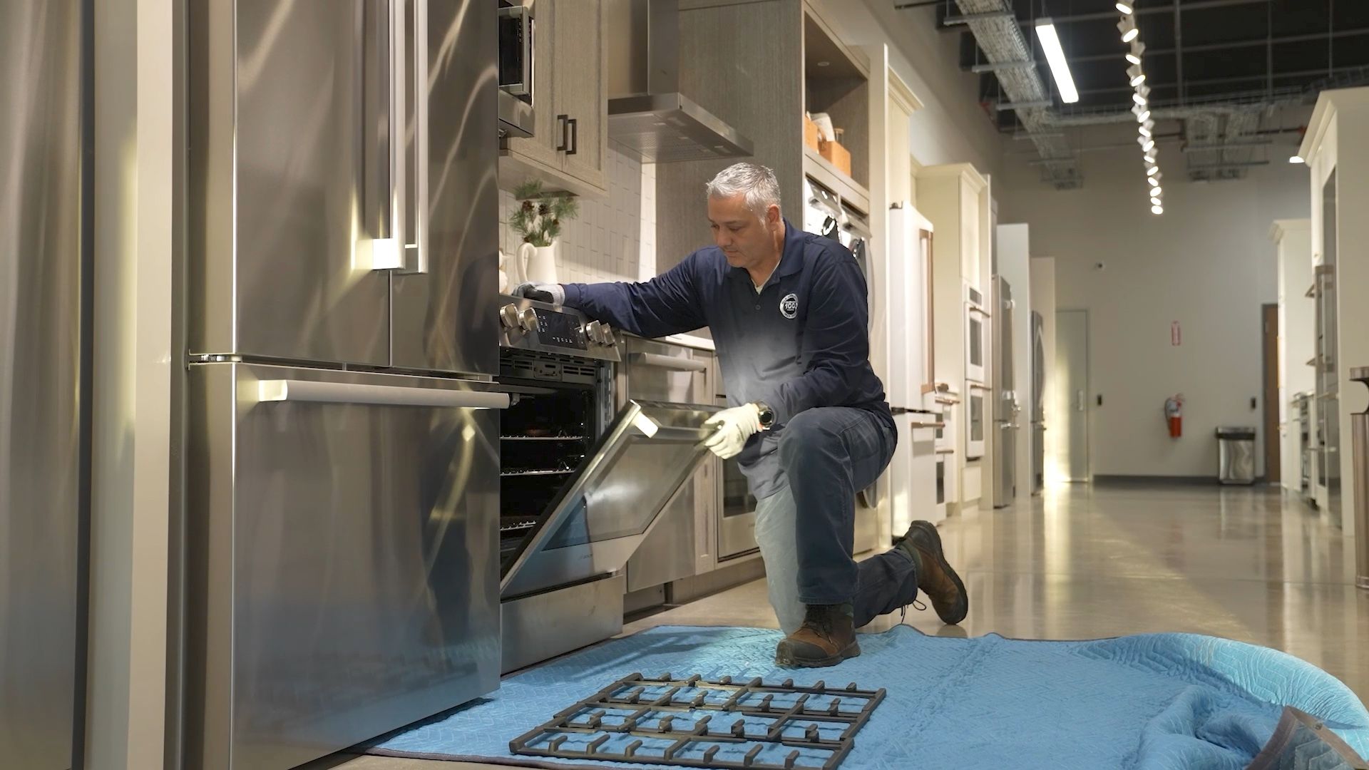A Yale Appliance technician kneeling beside a slide-in range with a flashlight, opening the oven door